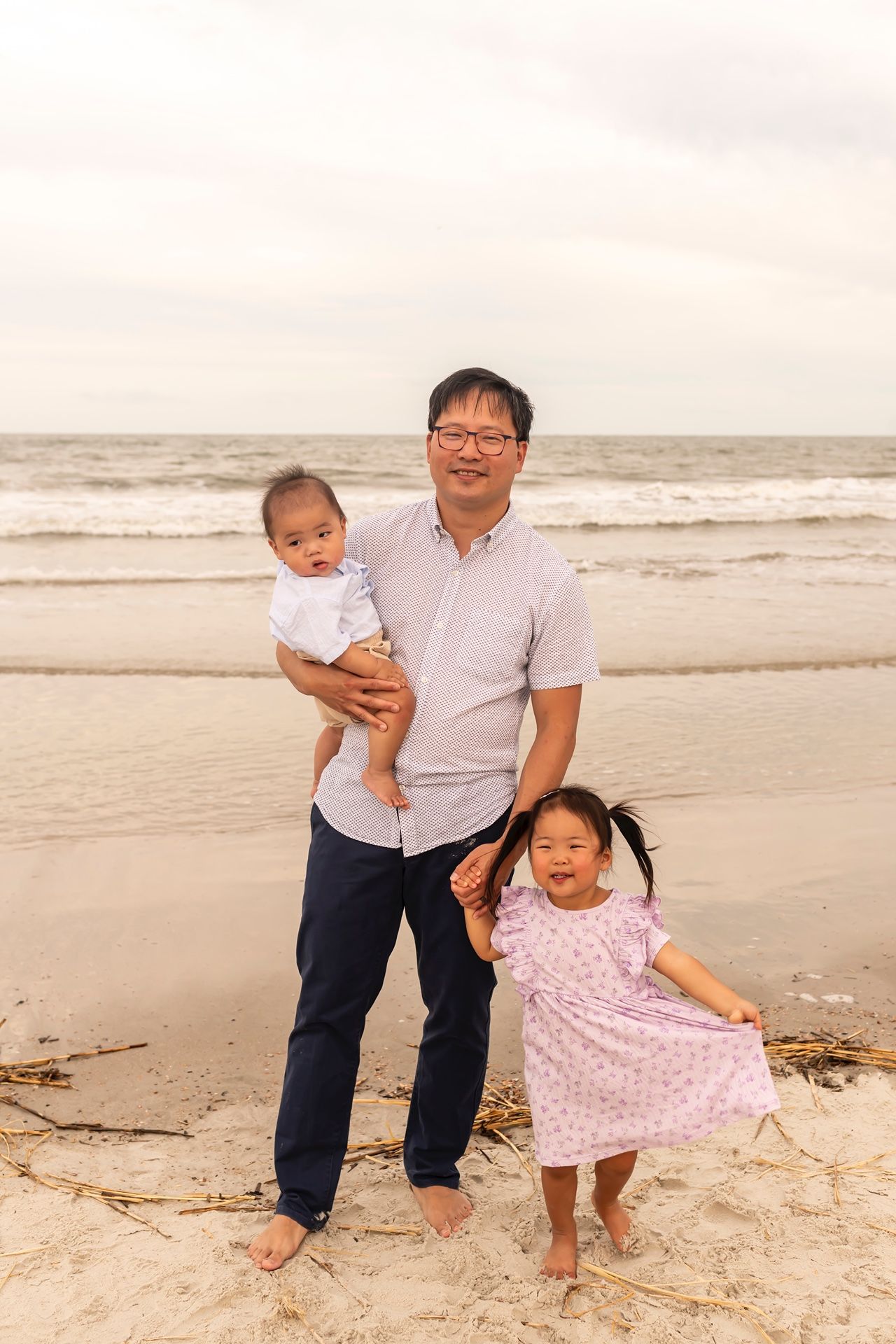 Family enjoying time together at the beach with children playing in the sand at sunset.