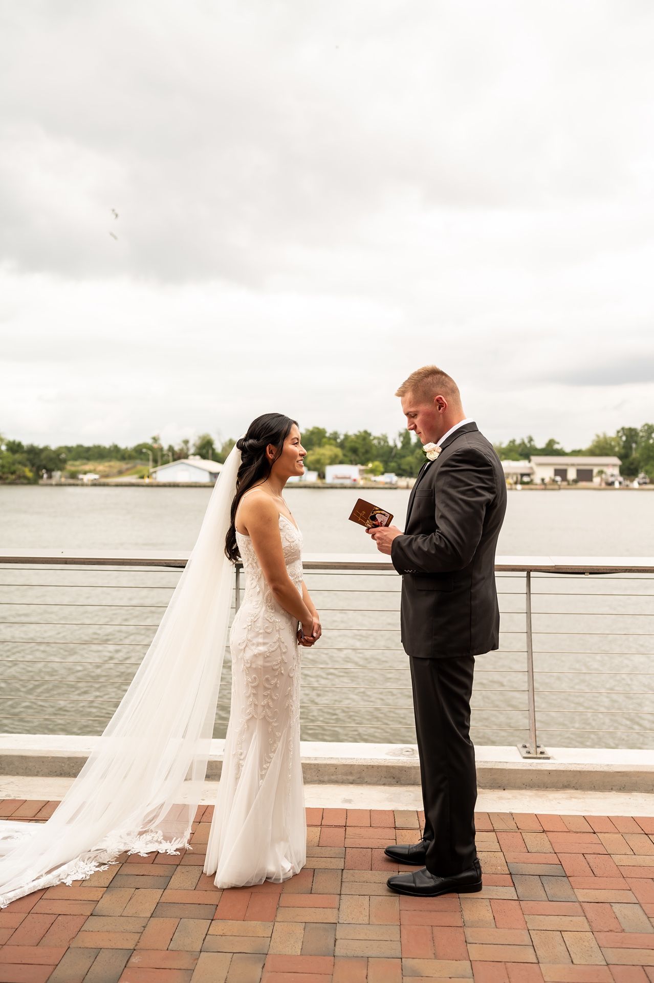 Happy couple stands by waterfront in formal attire as they celebrate during a wedding ceremony.