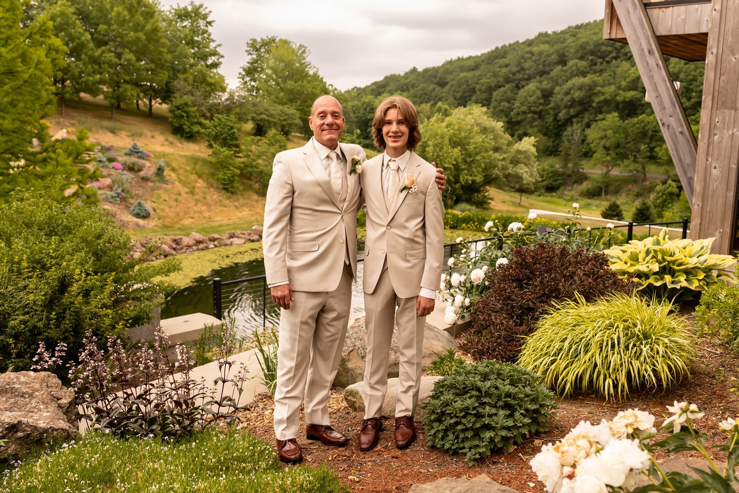 A couple in matching beige outfits poses in multiple scenic garden settings with lush greenery and landscaping.