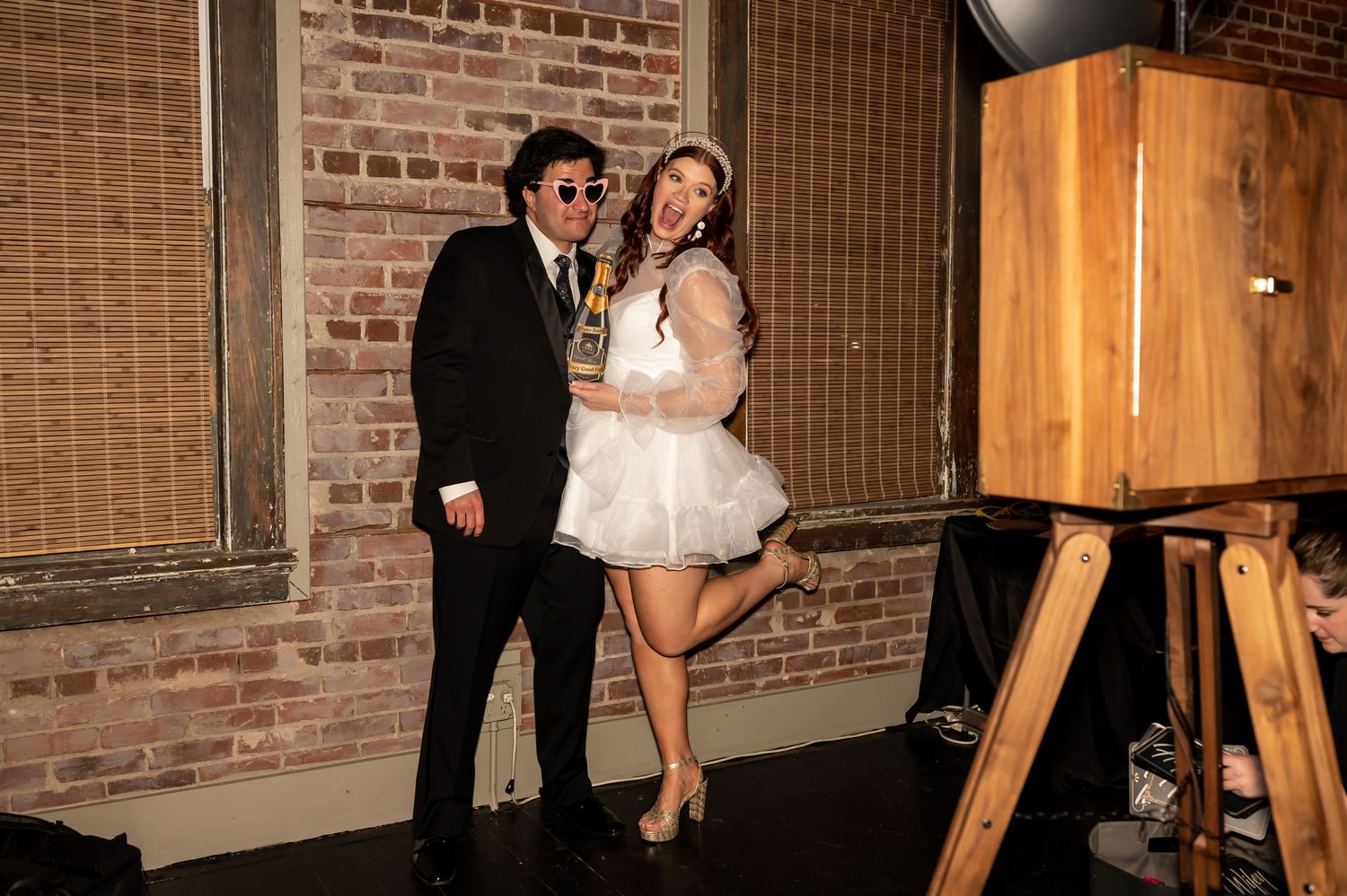 A couple poses and dances in their formal attire against an elegant brick wall backdrop at a wedding reception.