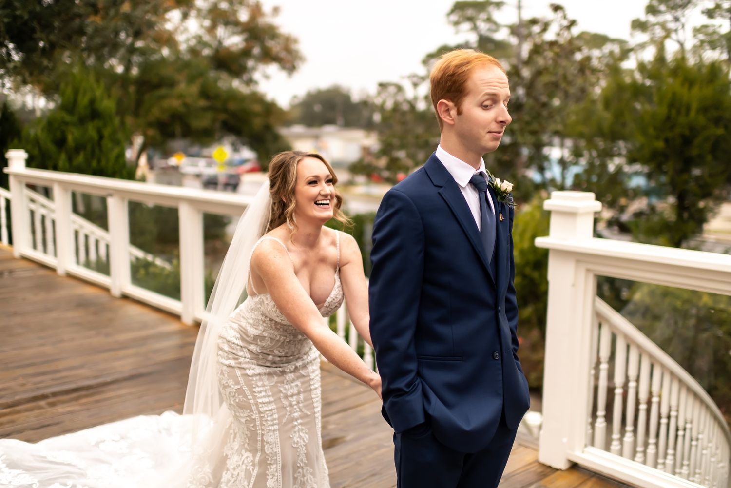 Wedding party posing on a wooden deck surrounded by lush greenery on a sunny day.
