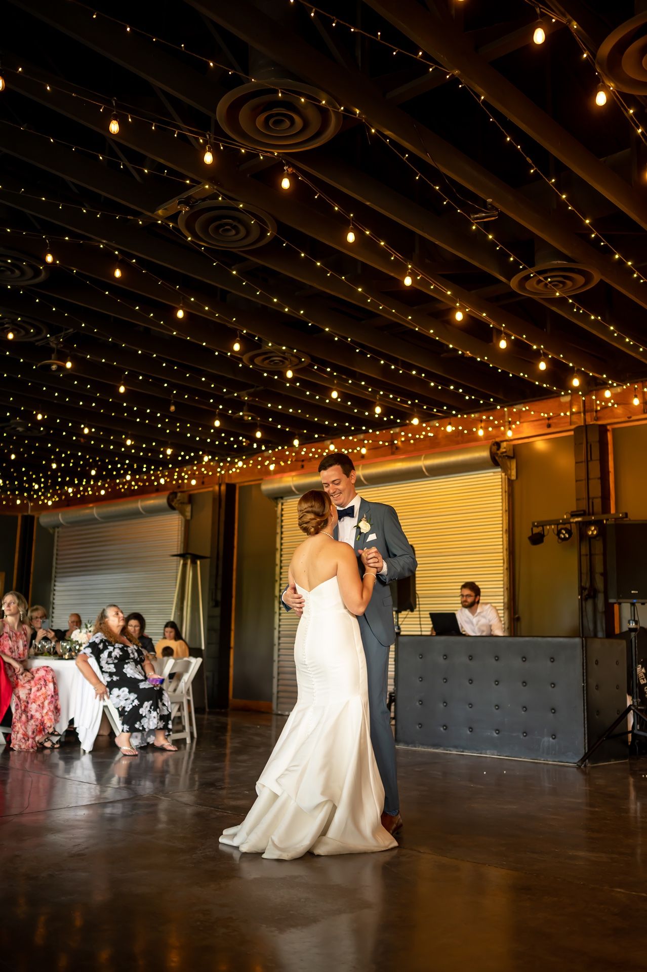 Two people share their first dance under a romantic starlit ceiling at an elegant wedding reception venue.