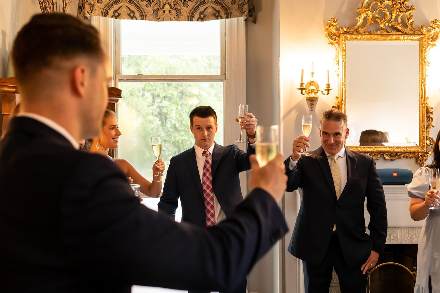 A row of formal photographs showing people in suits interacting at an elegant event with ornate decor and lighting.
