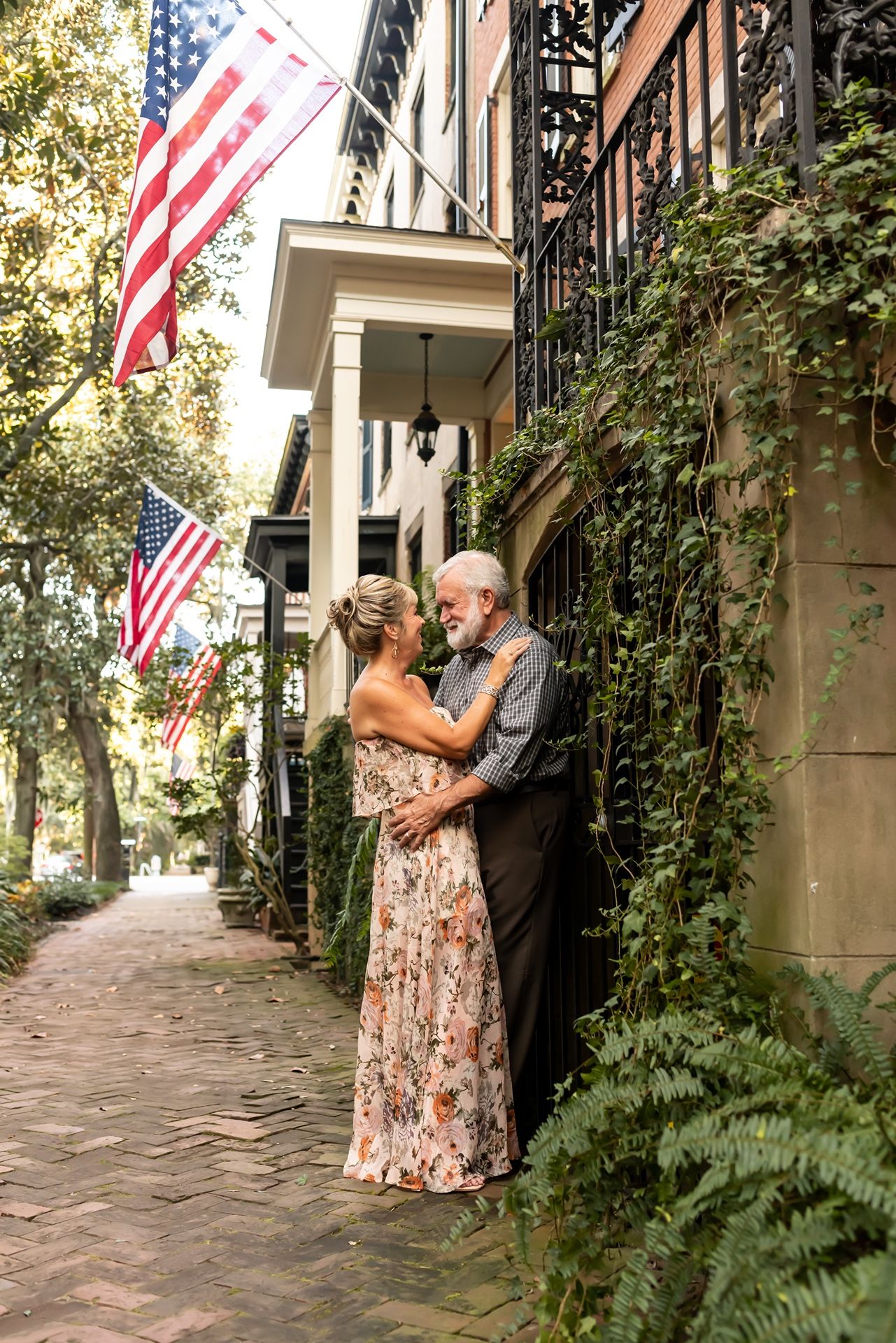 A romantic moment outside a historic brick building with American flags and ivy-covered walls along a brick sidewalk.