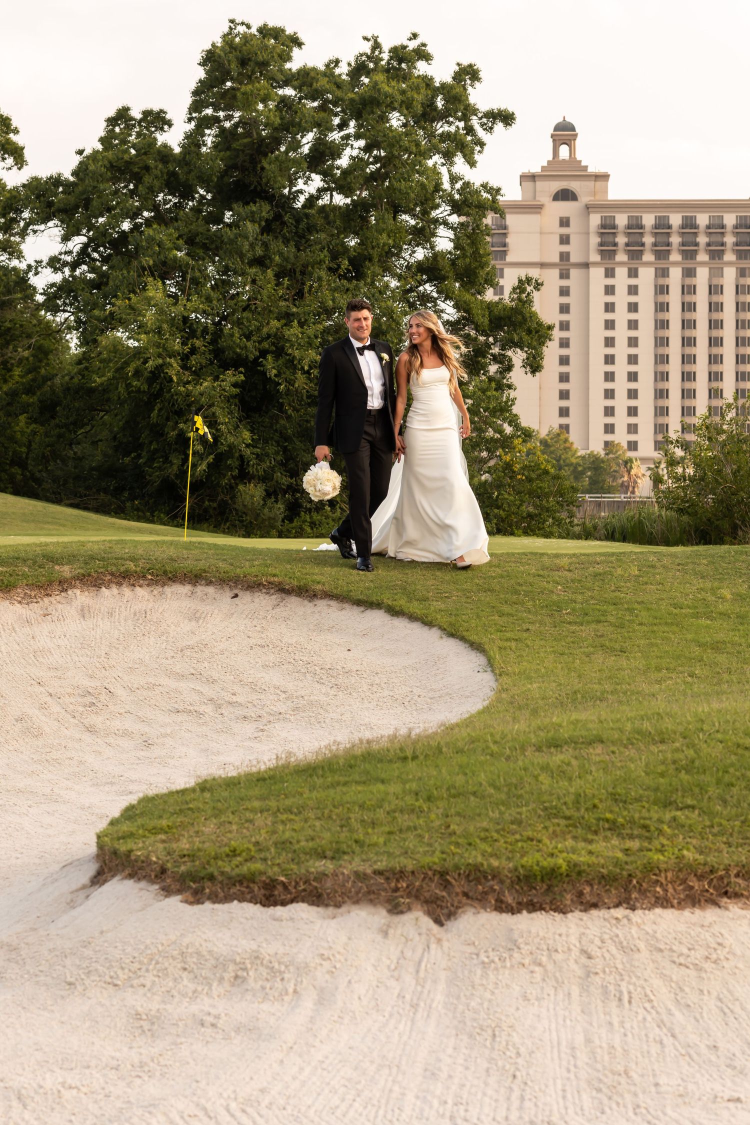 Wedding scene at golf course with sand bunker and Westin Savannah in background.