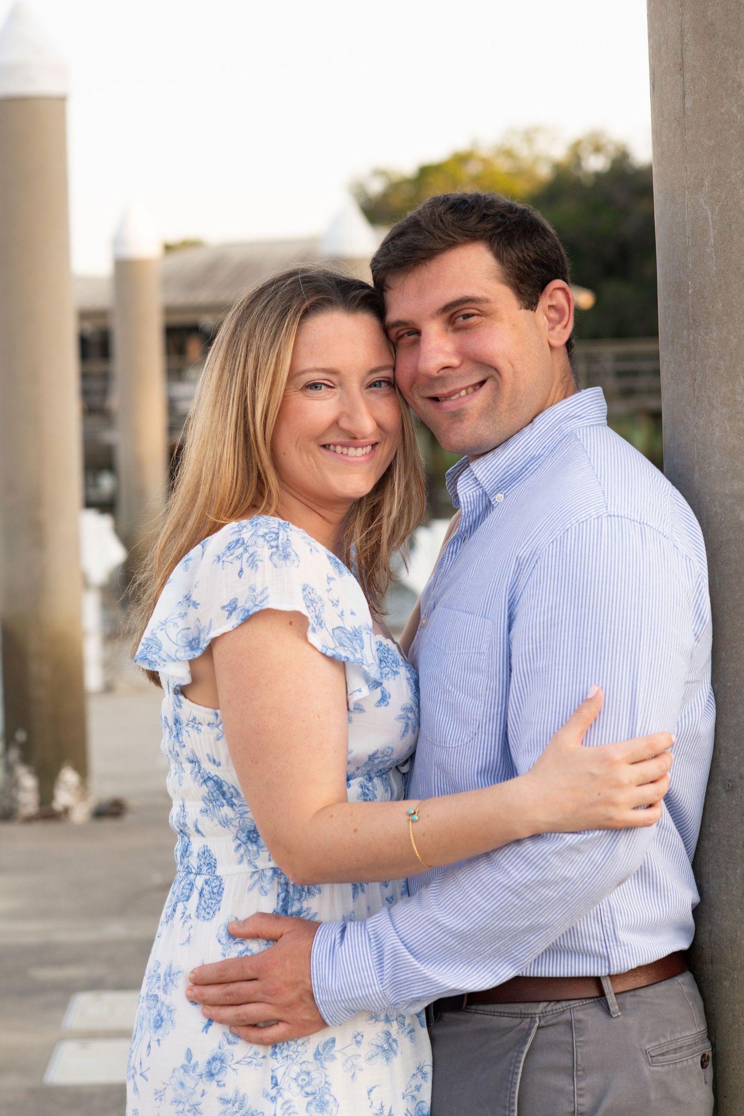 A couple embraces outdoors wearing coordinating blue and white outfits during a sunset photoshoot.