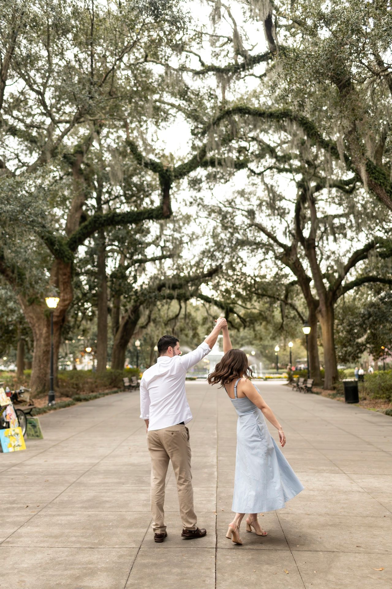 A couple performs a romantic dance sequence under Spanish moss-draped oak trees on a winding pathway.