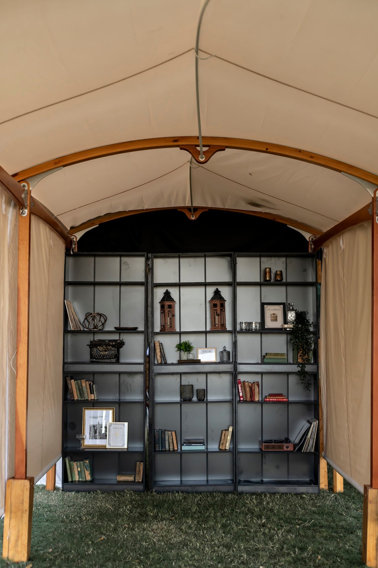 A panoramic view of modern black wall-mounted shelving units displaying books and decor against a white tent ceiling.