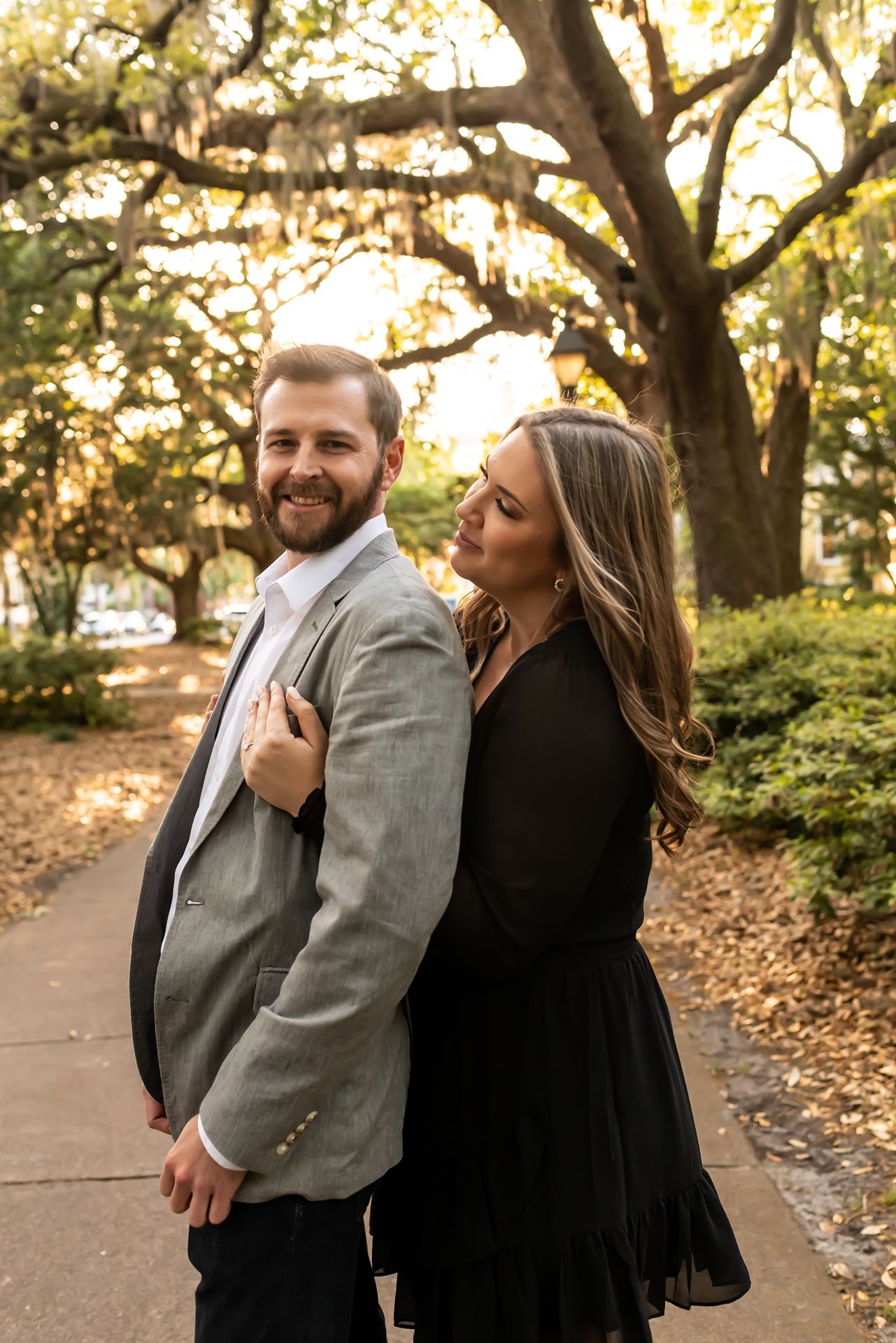 Happy couple shares laughter and joy during a romantic autumn photo session beneath golden trees.