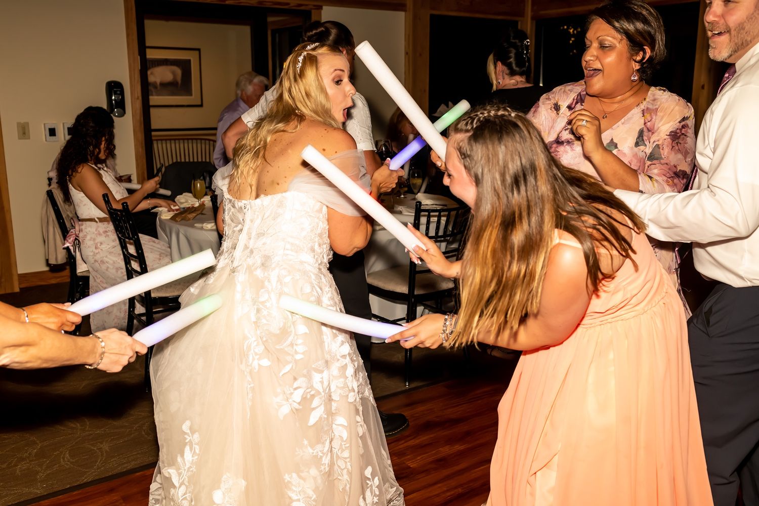 Dancers move across a wooden floor at a reception party while dressed in elegant attire.