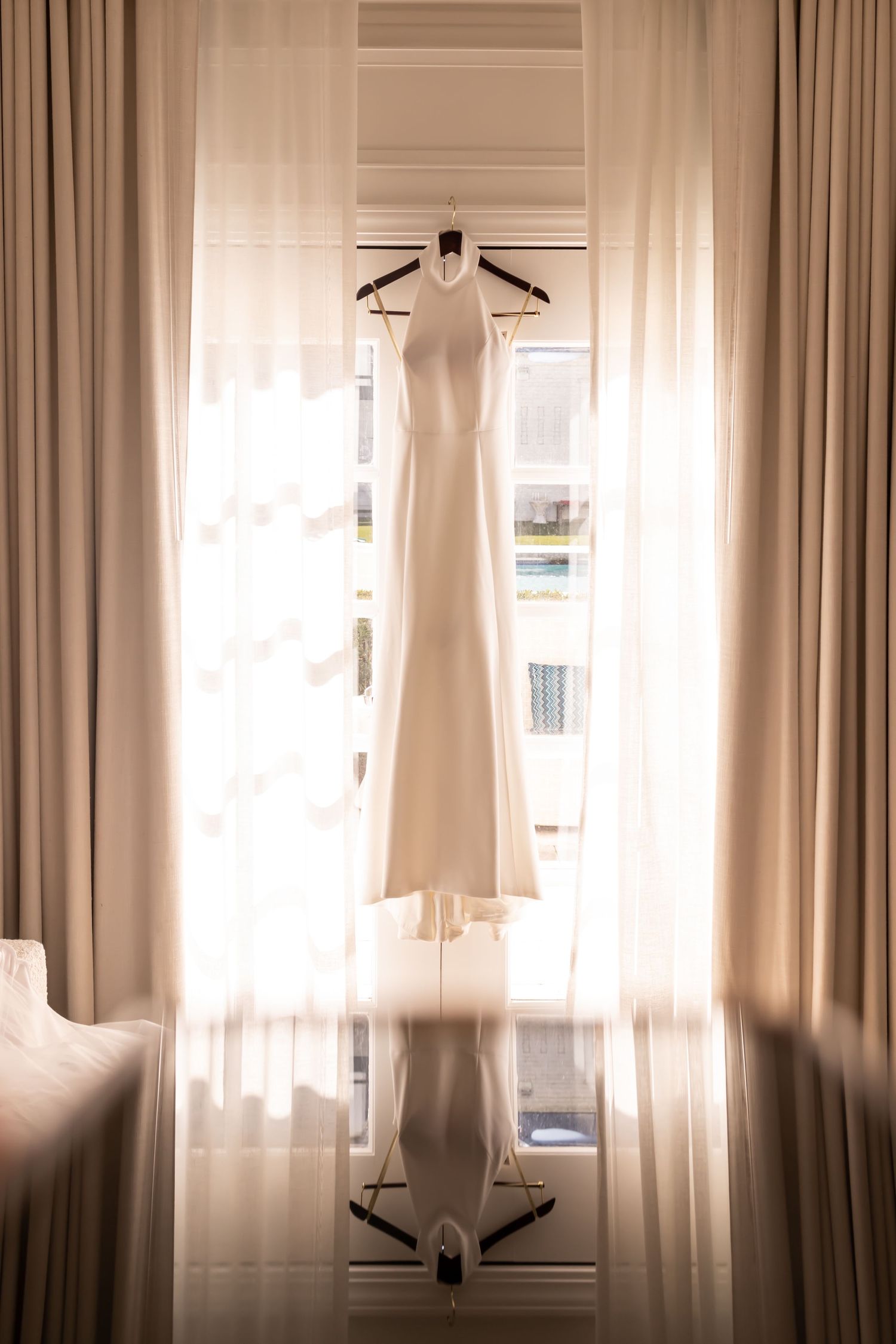 Three white curtain panels hanging in front of windows with sunlight filtering through the sheer fabric.