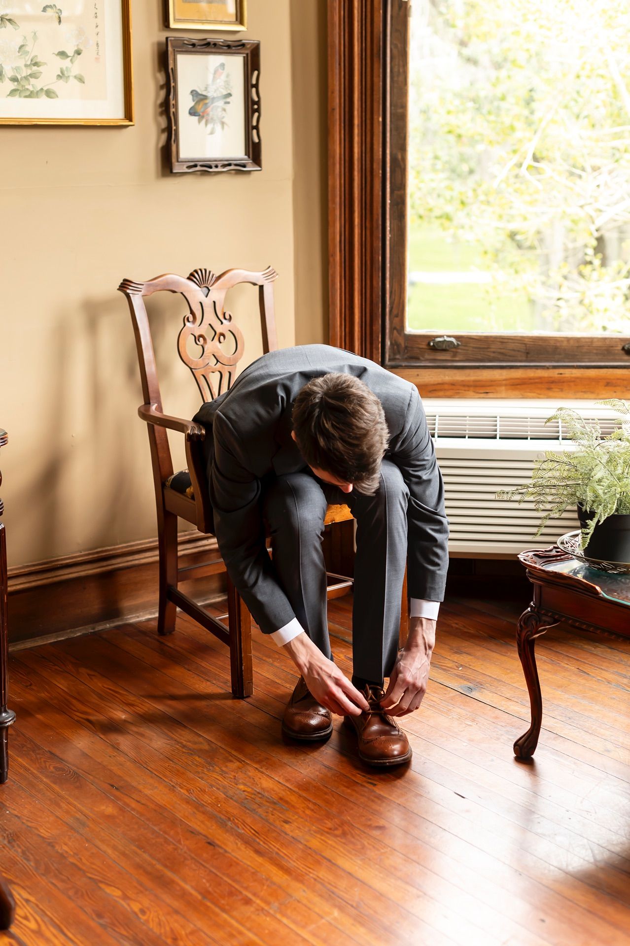 A sequence of photos showing someone in dark clothing folding themselves down while sitting on a wooden chair.