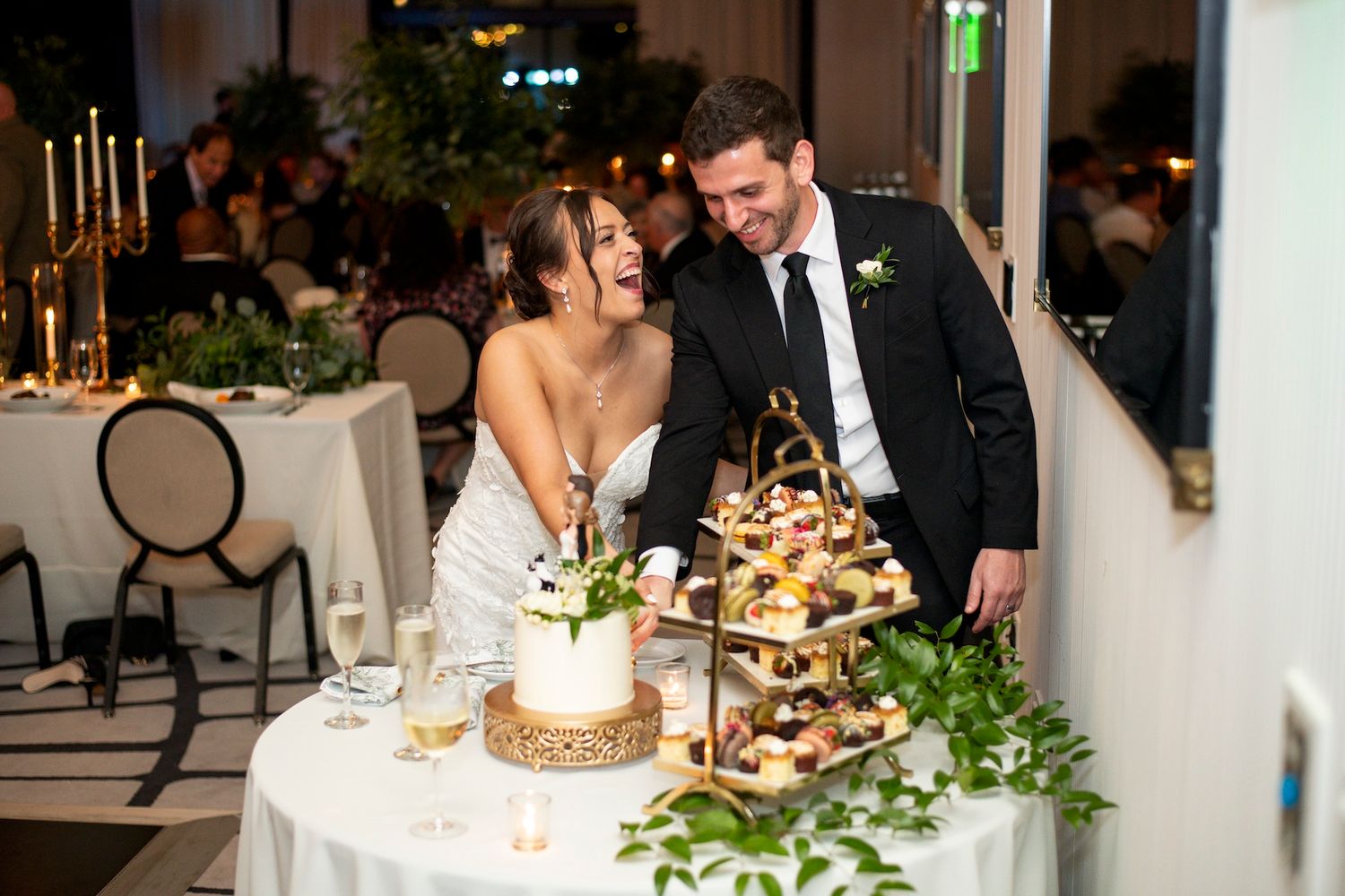 Elegant wedding reception table decorated with white floral centerpieces, candles and greenery in a sophisticated venue.