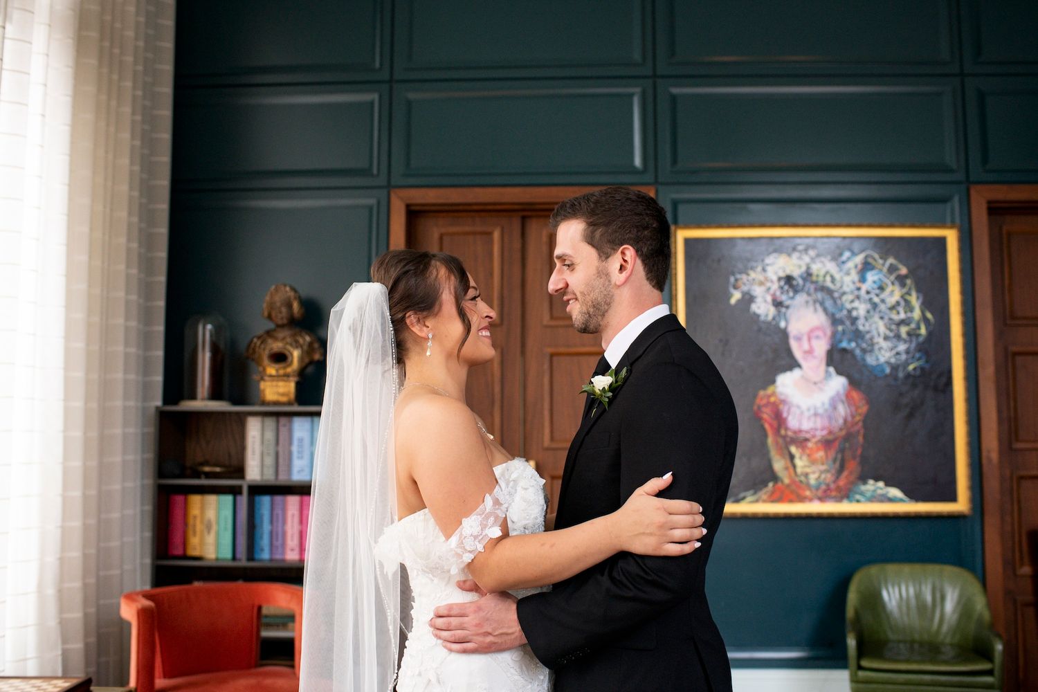 Two people share a romantic moment while dancing together in an elegant room with framed artwork on the walls.