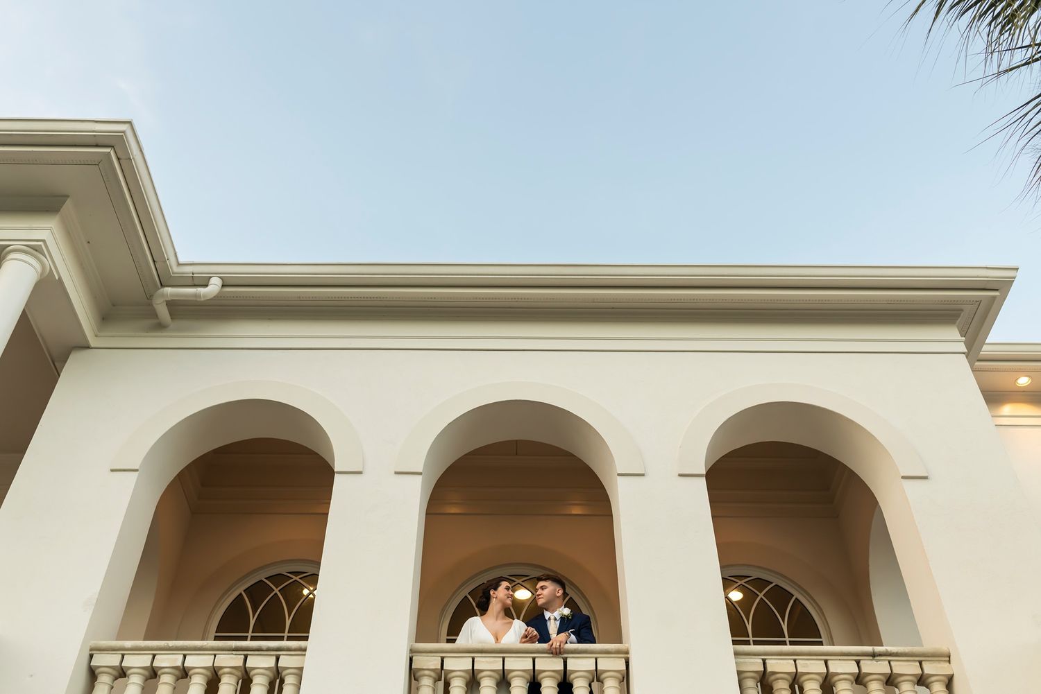 A serene beige stucco mansion with arched windows and balconies showcases elegant Mediterranean architecture.
