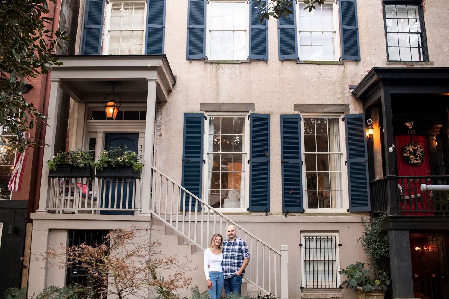 Row of historic brownstone buildings with black shutters and ornate architecture line Jones Street in Savannah, Georgia.