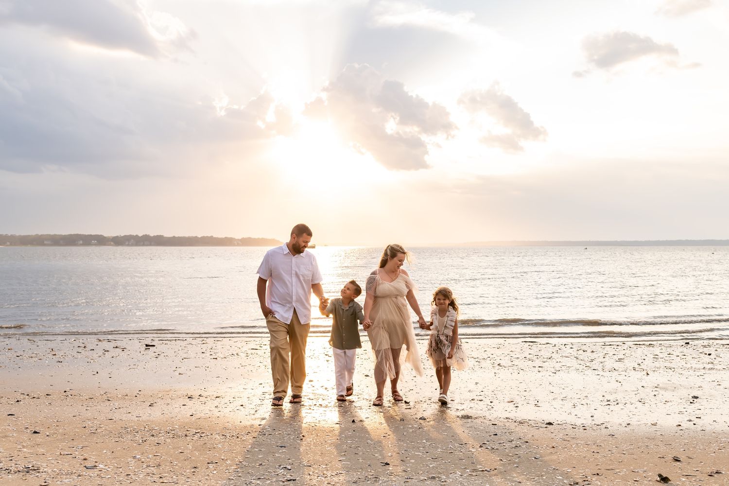 Silhouetted family holding hands while walking along a serene beach at sunset.