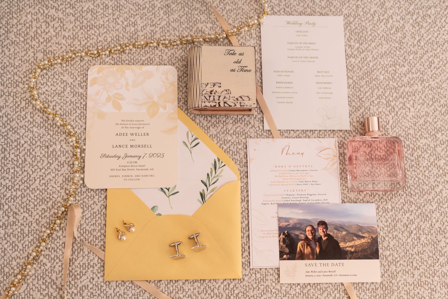 Wedding invitations and envelopes with floral designs laid out in a row on a gray textured surface.