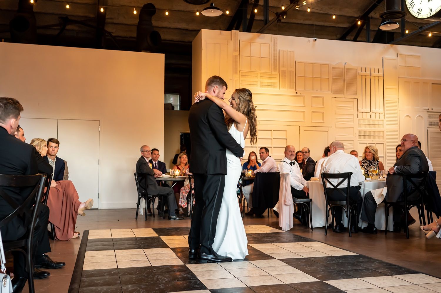Guests gather in an elegant banquet hall with soft lighting and wall art during a formal event celebration.