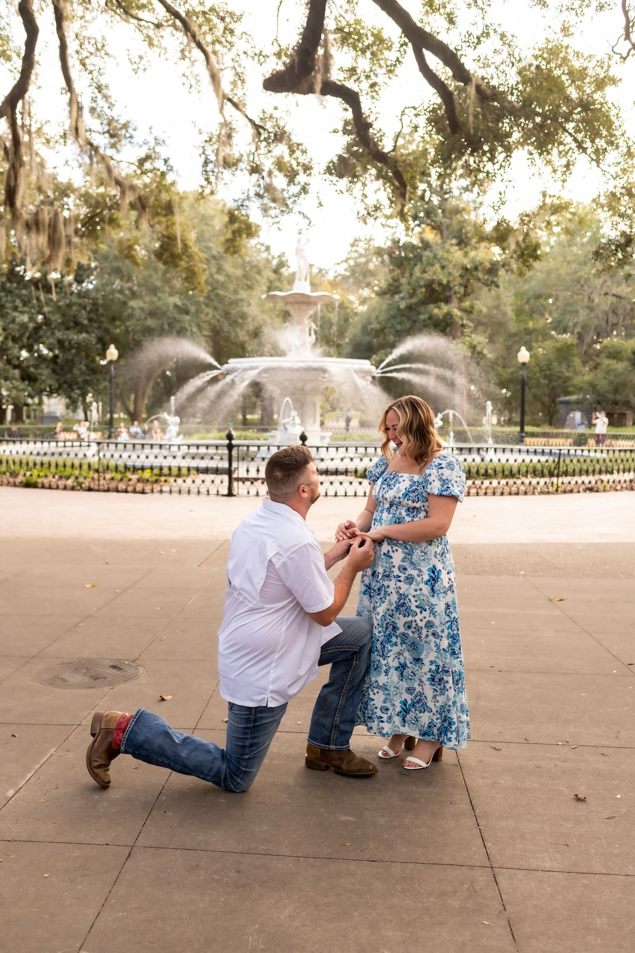 A couple shares a special moment during a marriage proposal at an outdoor plaza.