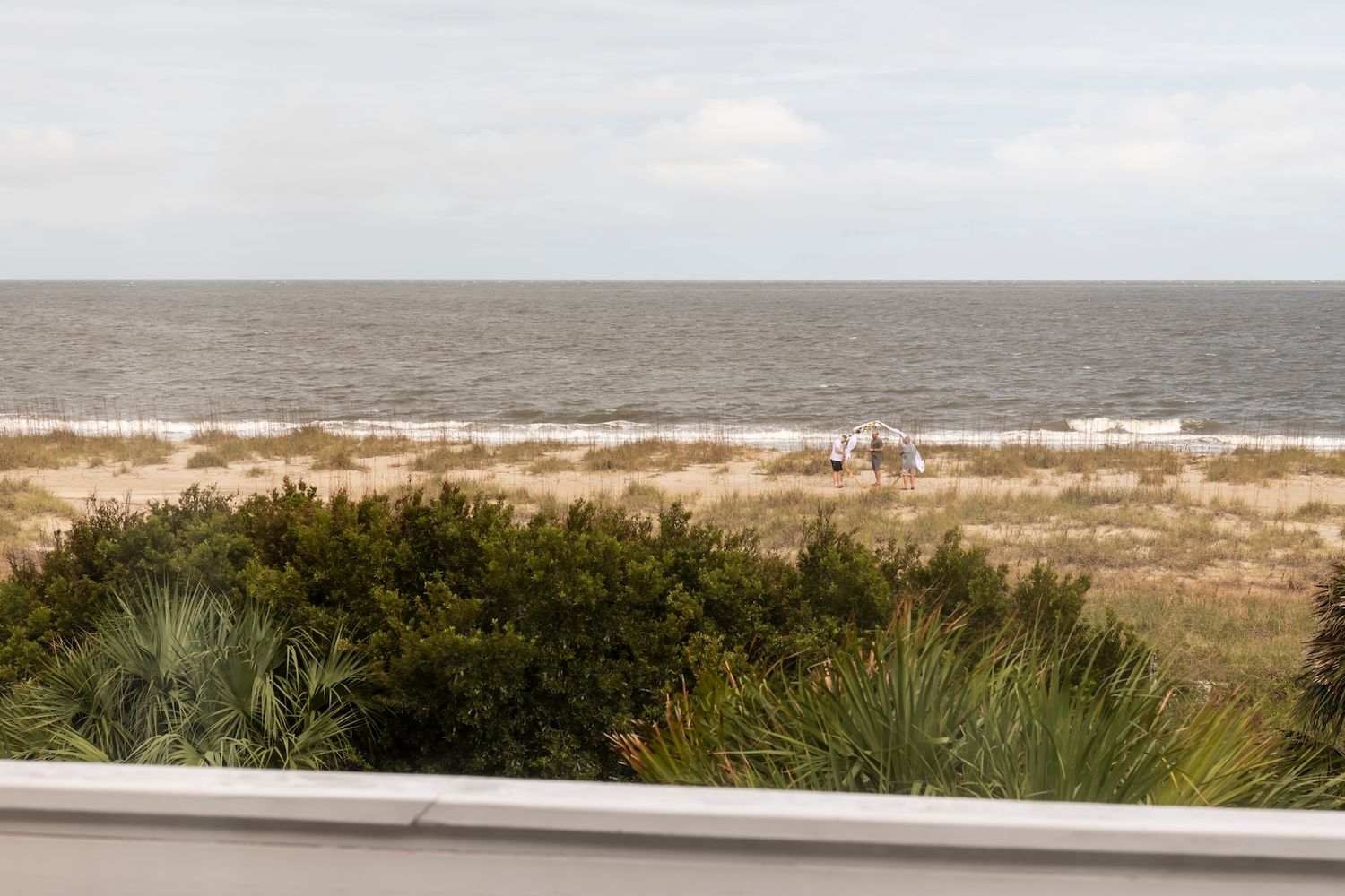 A peaceful coastal landscape with sand dunes, sea grasses, and the ocean stretching to the horizon.