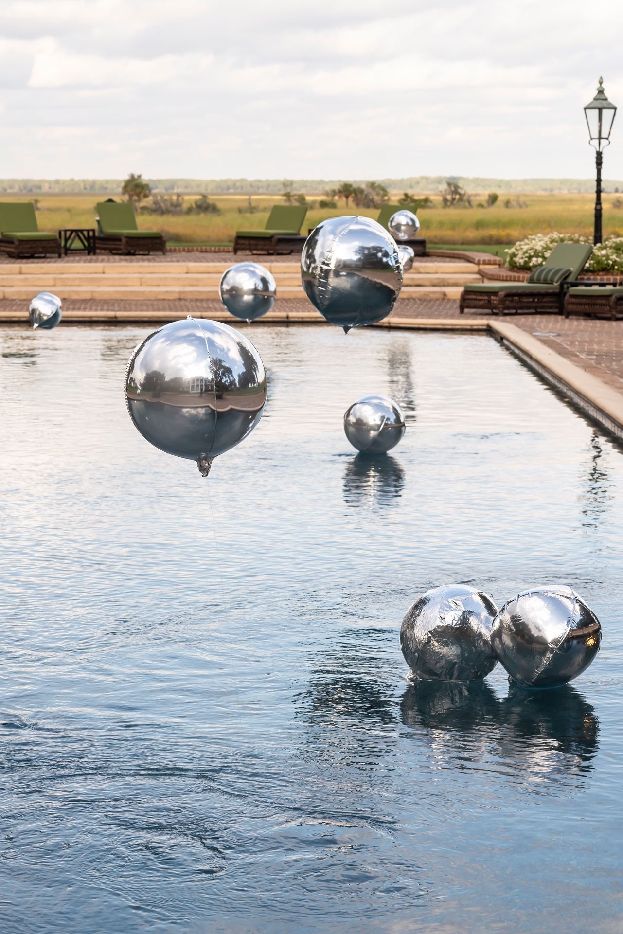 Large reflective silver spheres float artistically in a tranquil pool of water creating a modern sculptural installation.