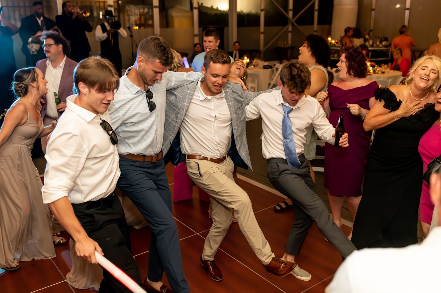 Party guests line up and dance in sync at an indoor event with coordinated group dance moves.
