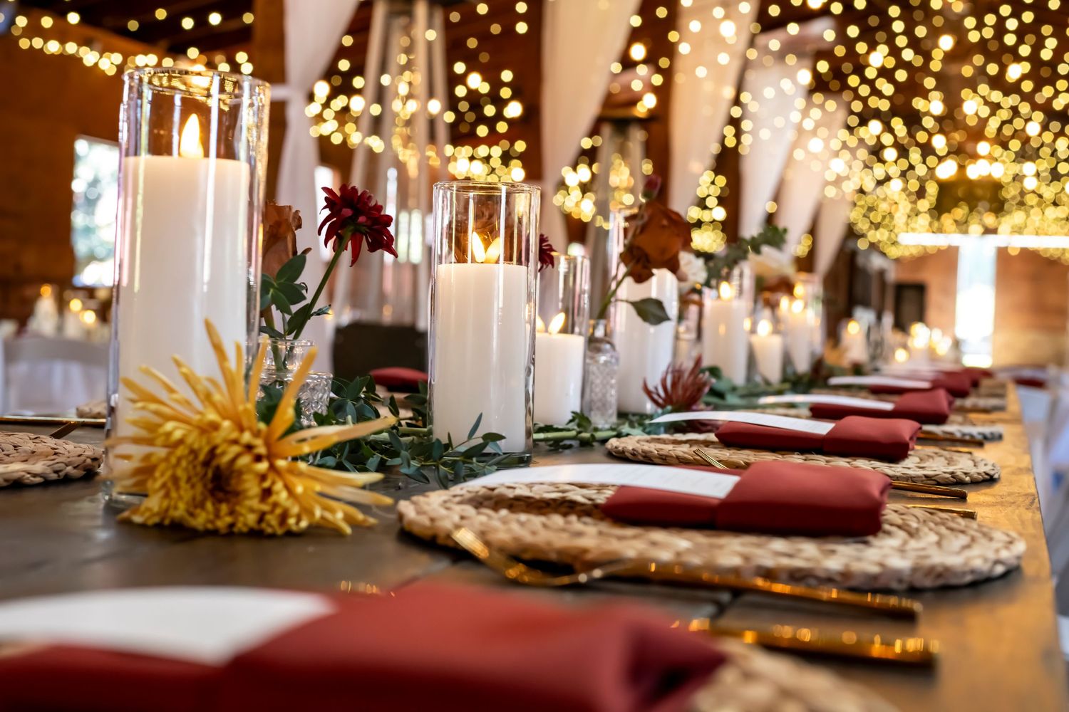 Romantic wedding reception table setting with string lights and floral centerpieces.
