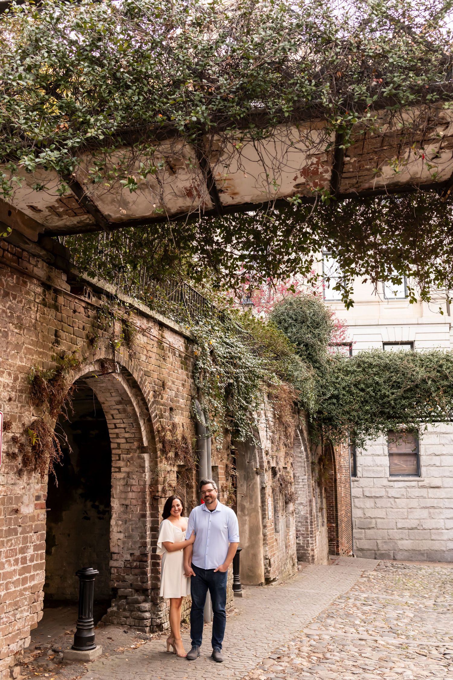 A stone archway walkway covered in climbing vines creates a romantic atmosphere in a historic courtyard.