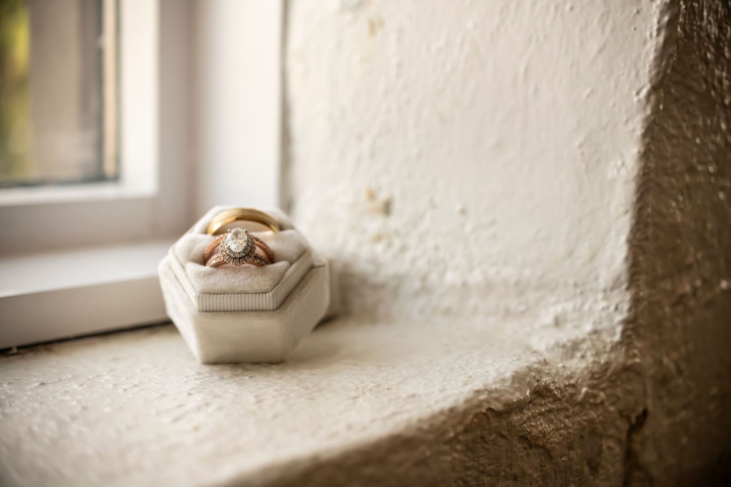 Wedding rings in a white ring box on a window sill.