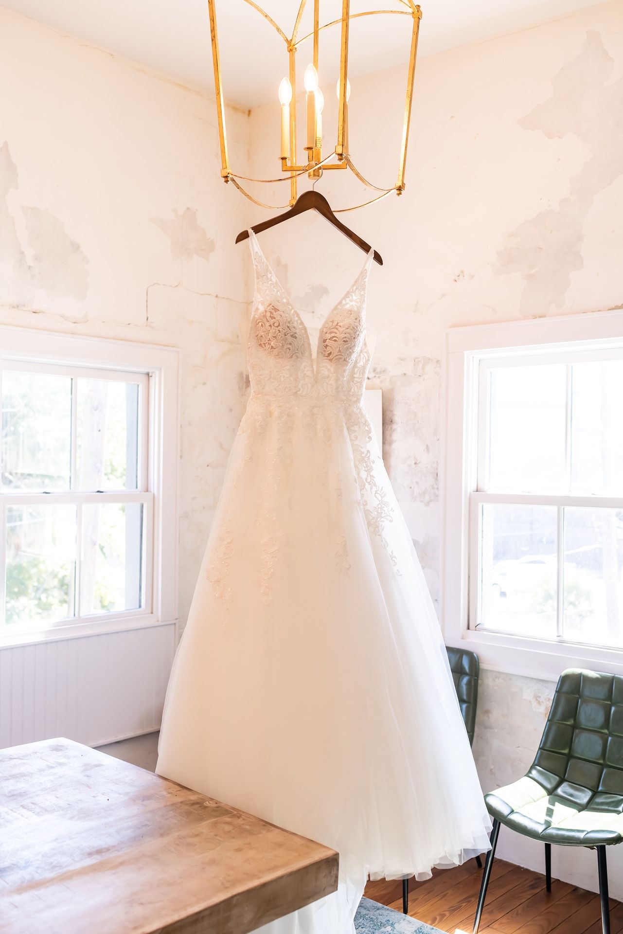 Elegant white wedding dresses displayed on hangers in a bright, minimalist bridal boutique interior with natural lighting.