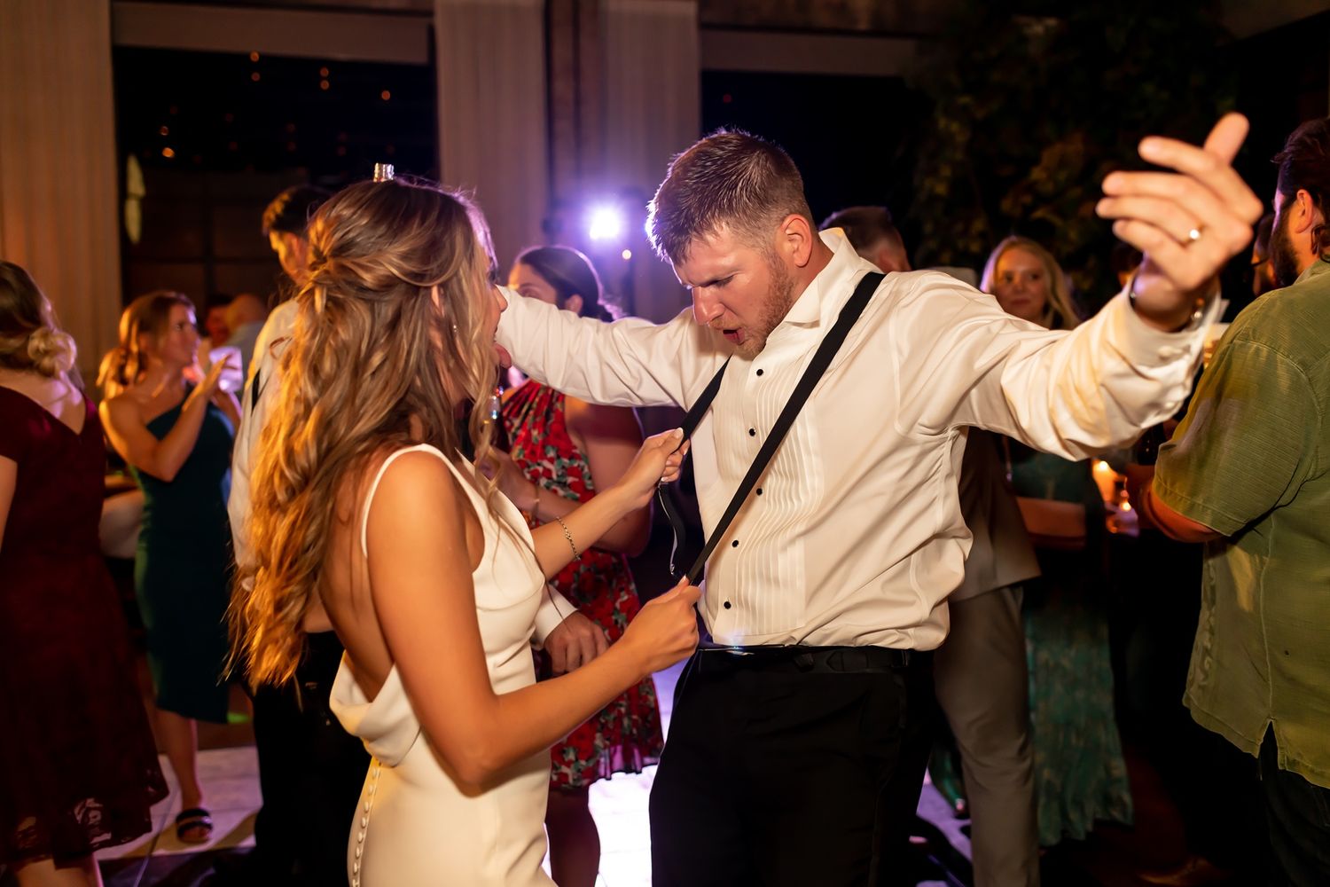 Couples dancing together at an elegant evening wedding reception in a dimly lit venue.