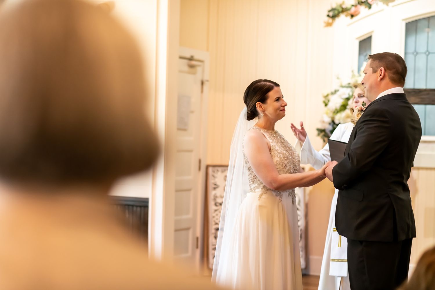 A couple shares an emotional moment during their intimate indoor wedding ceremony as guests look on.