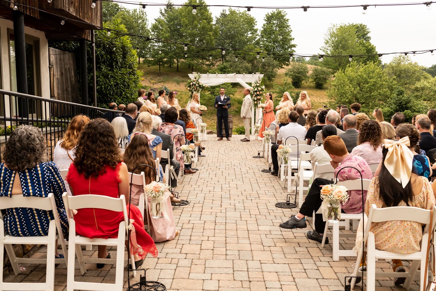 Guests gather on an outdoor patio with string lights during a summer evening event.