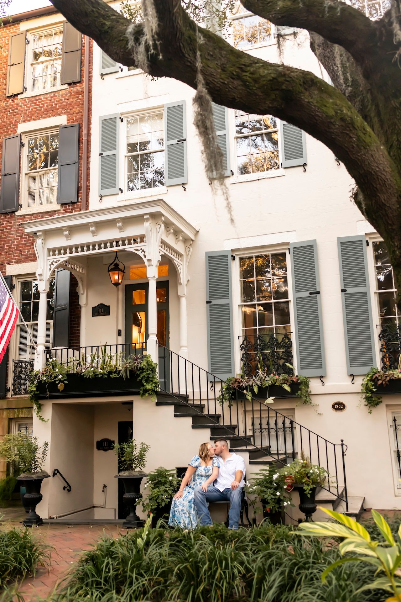 A charming historic townhouse with gray shutters and an American flag features ornate architectural details and a grand staircase.