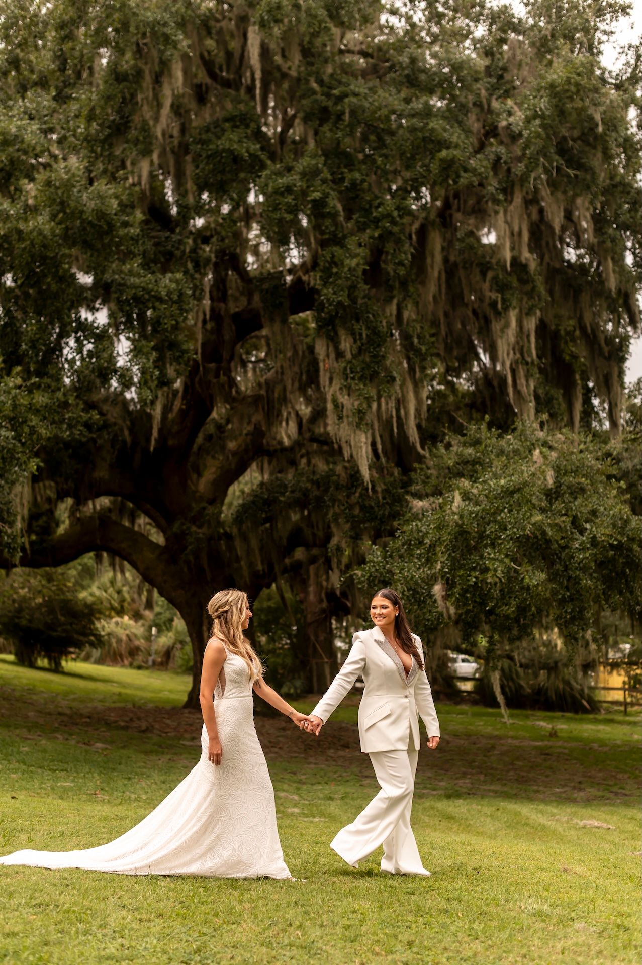 Two brides walk across the lawn at their Red Gate Farms wedding.