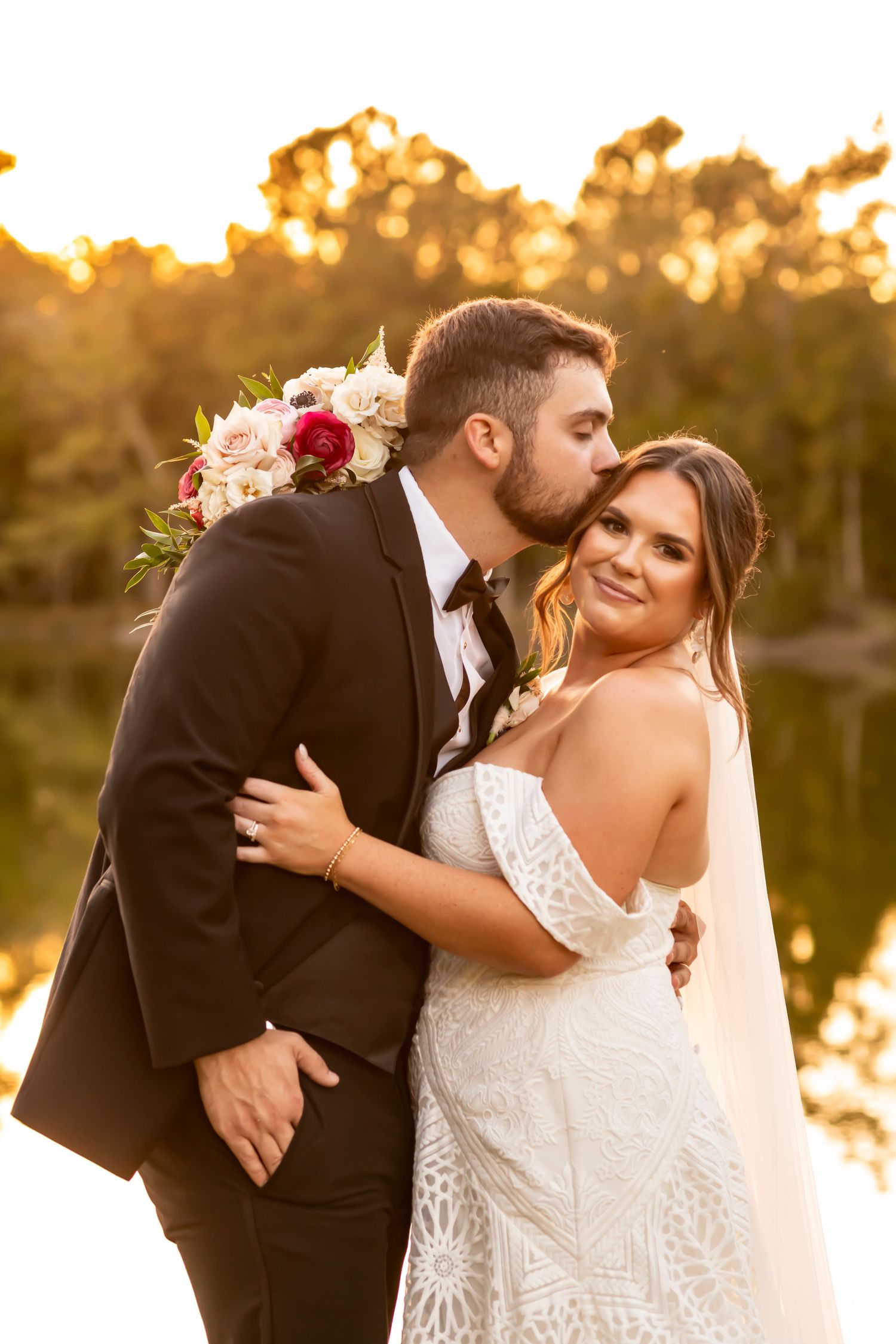 Romantic sunset wedding portraits by a lake with golden light.