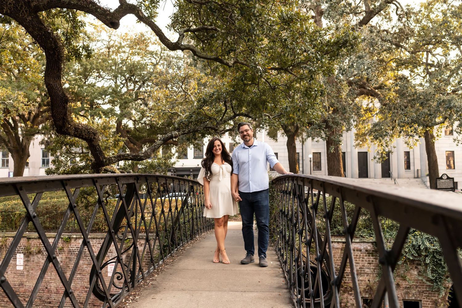 Walking couple on a rustic bridge with wrought iron railing on Factor's Walk in Savannah, Georgia