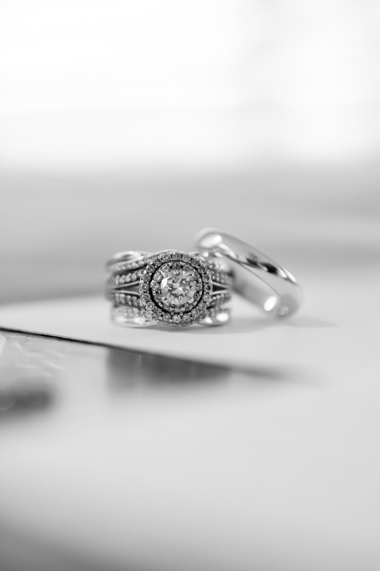 Black and white photo of an elegant diamond engagement ring with beaded edges shown at different angles and depths of field.