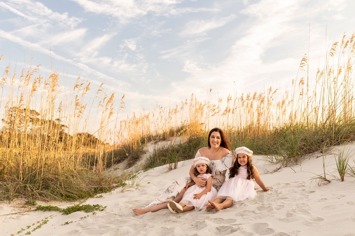 Group sits together in natural seating area on sandy beach dunes with sea oats swaying in golden sunlight.