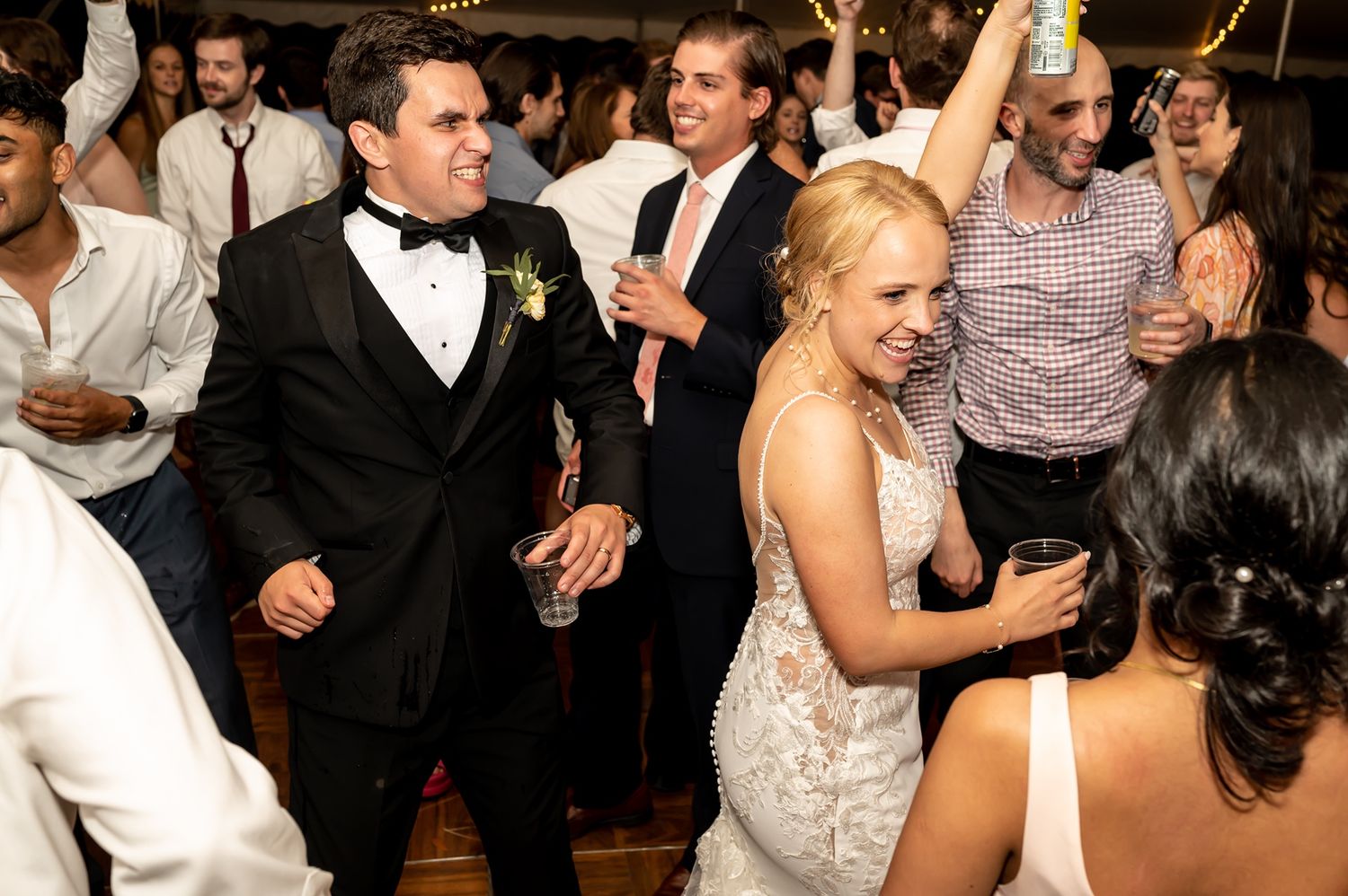 Wedding reception guests celebrating with enthusiastic dancing and movement on a crowded dance floor.