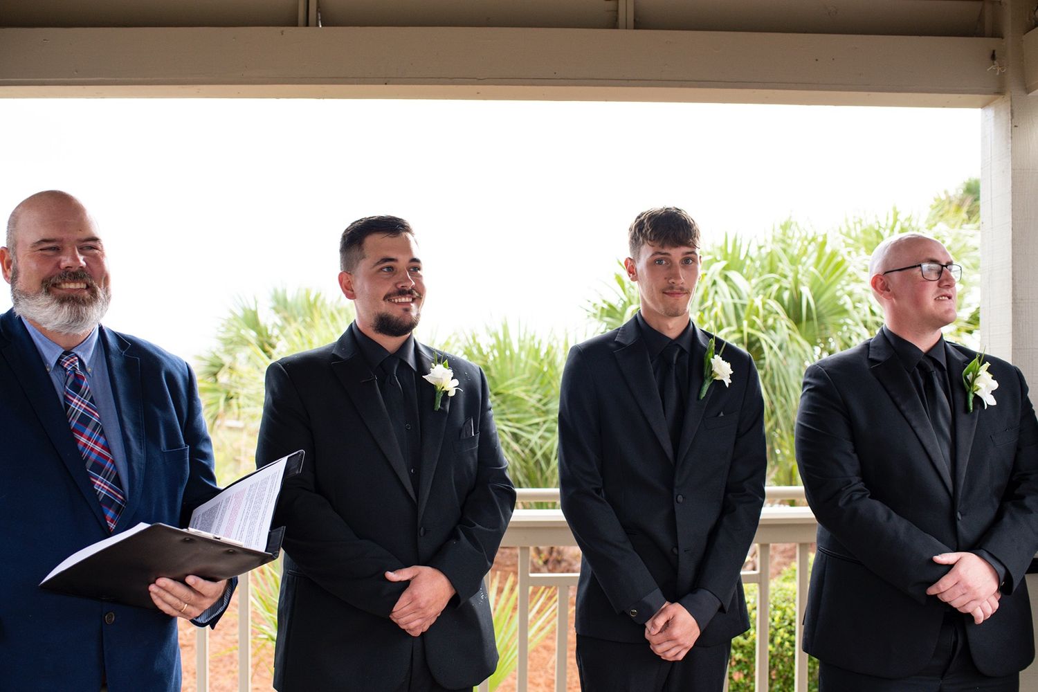 A row of men in formal black suits and ties standing together at an event.