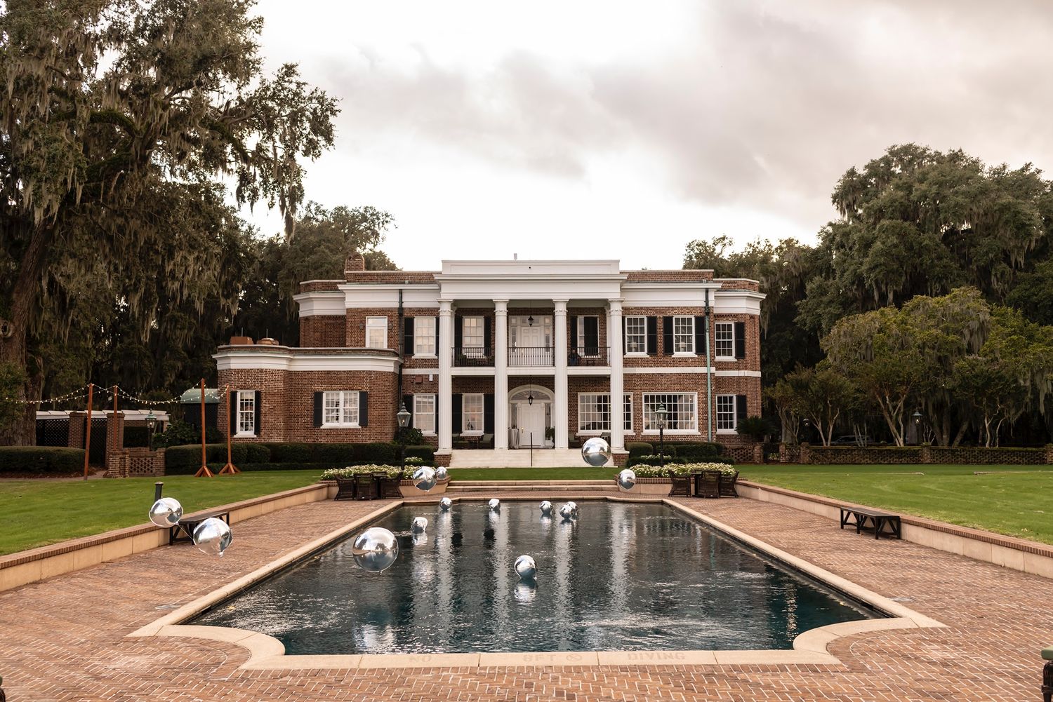 An elegant rectangular swimming pool surrounded by brick pavers at a historic estate.