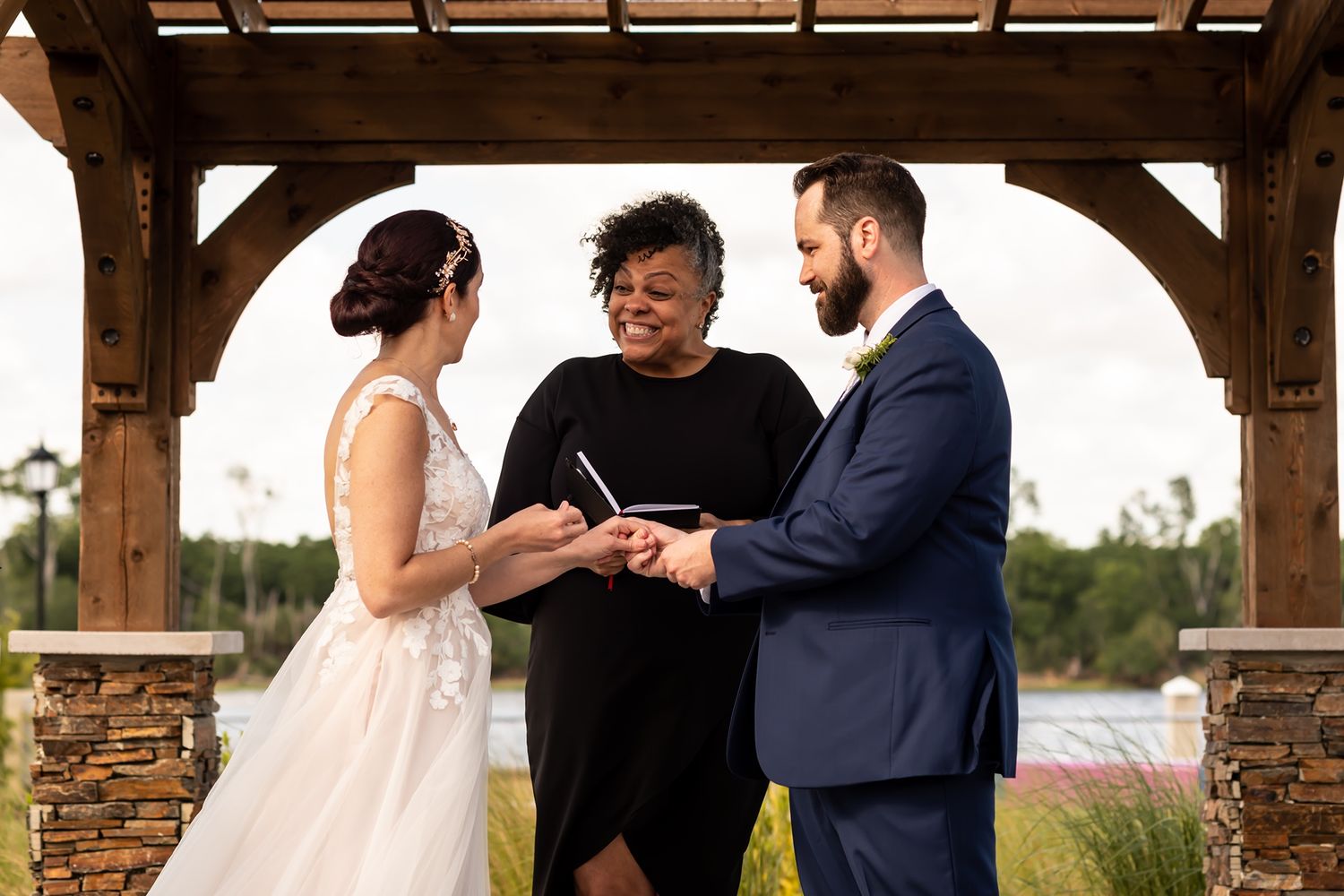 Newlywed couple shares intimate moments under a rustic wooden pavilion during their outdoor wedding celebration.