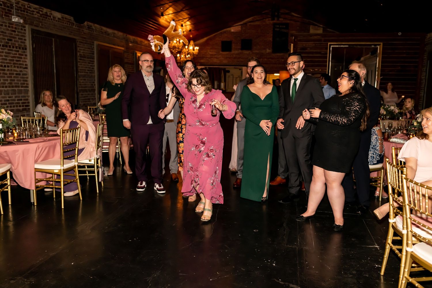 People dancing and enjoying themselves on a dimly lit dance floor at a formal event.