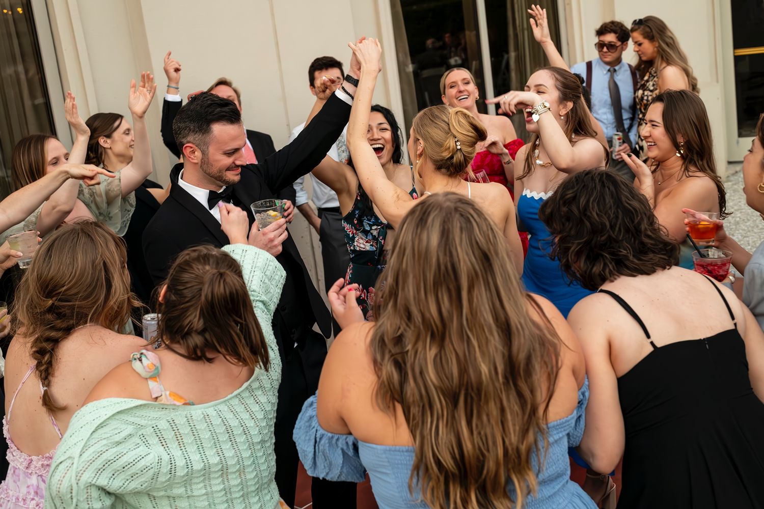 A lively group of party guests dancing and celebrating together on a dance floor at a formal event.