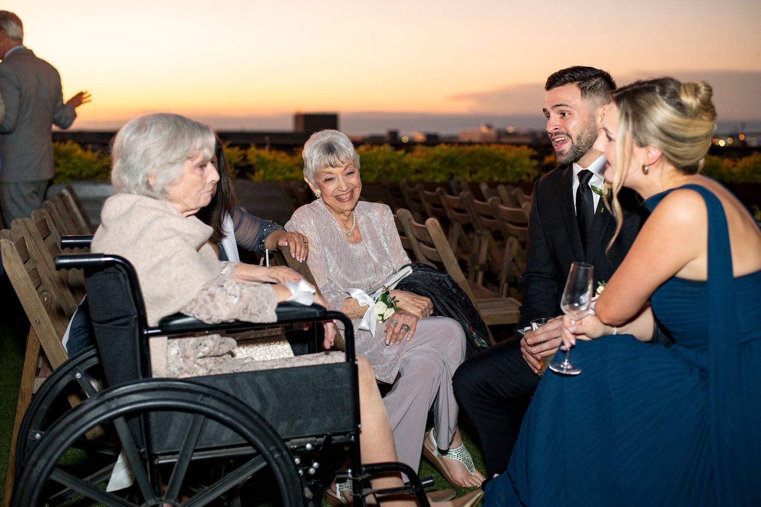People enjoying wine and conversation during an outdoor sunset gathering at a vineyard.