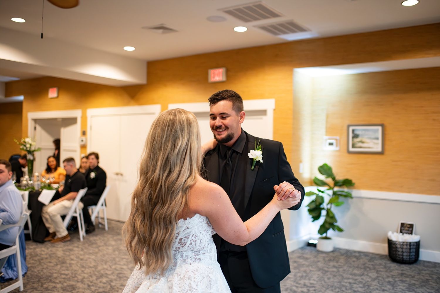 Wedding guests dance and celebrate in a warmly lit venue with wood paneled walls.