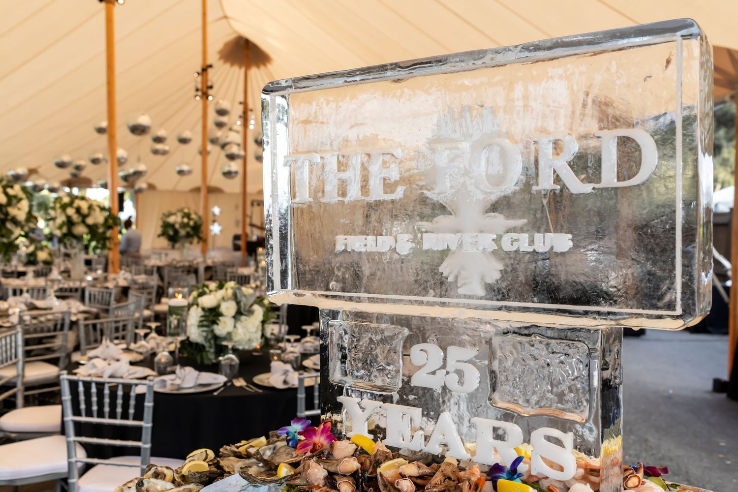Elegant ice sculpture reading 'The Ford' on decorated dining table at formal event.