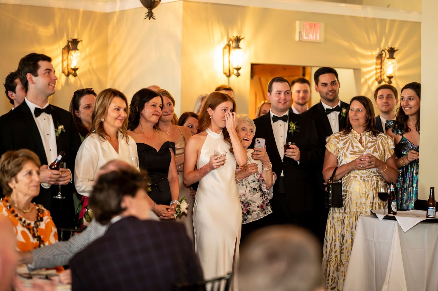 Wedding guests gathered together during an elegant indoor reception with warm lighting and formal attire.